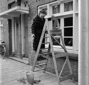 125755 Afbeelding van een vrouw op een trap tijdens het lappen van de ramen van het huis Boomstraat 9 te Utrecht.N.B. ...